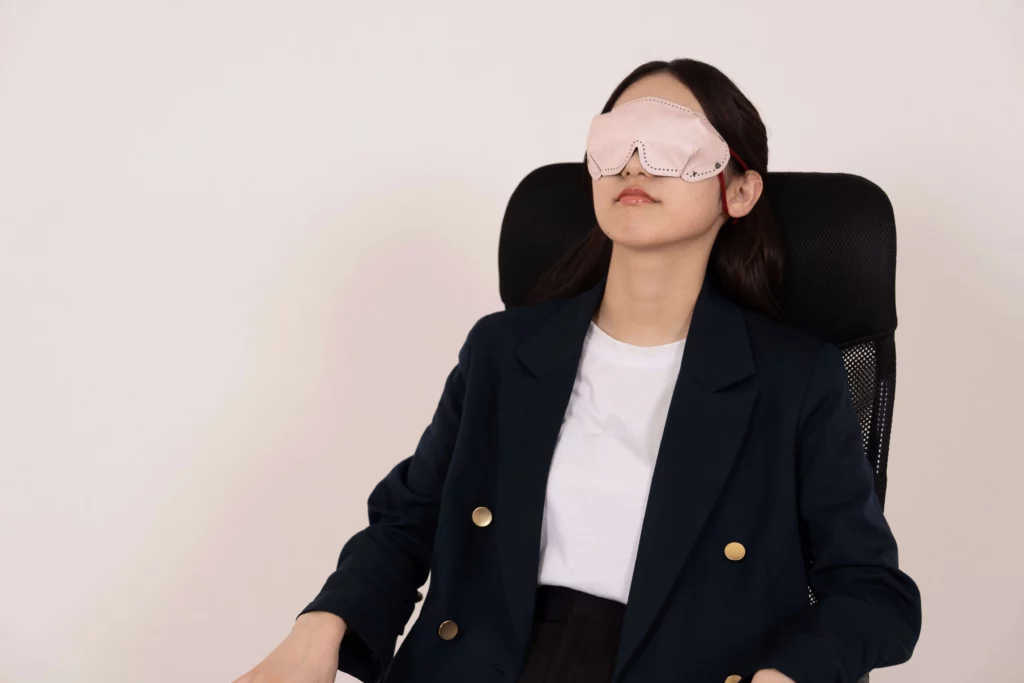 アイマスクをして椅子に座ったまま仮眠を取る女性
