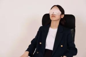 アイマスクをして椅子に座ったまま仮眠を取る女性